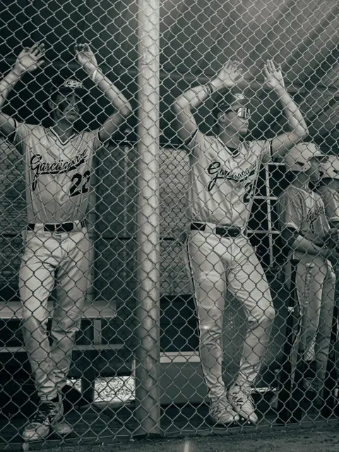 GBG Colorado players in the dugout looking through the chain-link fence